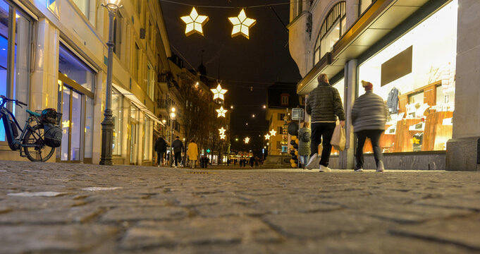Blick &uuml;ber das Kopfsteinpflaster der beleuchteten Kapellgasse in Luzern mit weihnachtlicher Sternenbeleuchtung bei Nacht