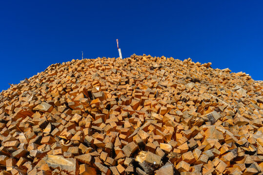 Riesiger Haufen aufgeschichtetes Brennholz aus der Froschperspektive unter strahlend blauem Himmel