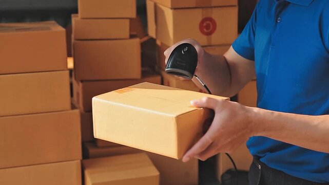 Warehouse worker scanning a parcel with a barcode scanner to track delivery in a logistics center with cardboard boxes in the background