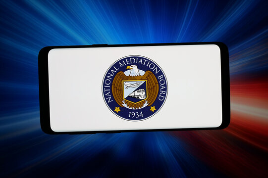 Stuttgart, Germany - 06-15-2026: In this photo illustration, the logo of US agency National Mediation Board (NMB) is displayed on a smartphone in front of abstract background on computer screen.