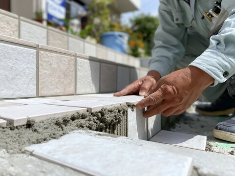 屋外で日本の男性職人が丁寧に住宅の階段タイルを施工する手元