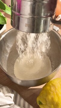 Sifting flour with a sifter into a metal bowl for baking