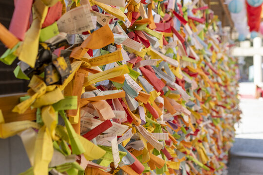 View of colorful omikuji fortune-telling paper strips tied to a wooden frame at a traditional Japanese shrine in Osaka, Osaka, Japan.