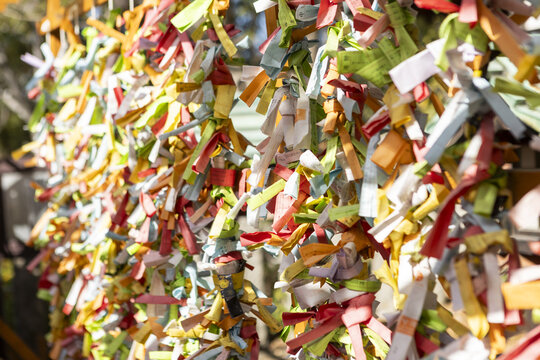 View of colorful Omikuji paper strips tied to a wooden frame at a traditional Japanese shrine in Osaka, Osaka, Japan.