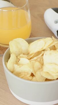 Vertical video: Sliding camera showing bowl of chips at home, centering juice, exposing pad for ad