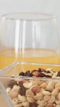 Vertical video: Panning camera from controller closeup, centering bowl with nuts and juice on table