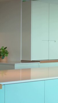 Vertical video: Panning camera right showing white cabinet at island for detail, plant, coffee