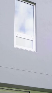 Vertical video: Tilting camera showing gray gable window sliding door, showing sofa, plants at home