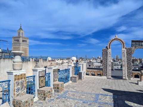Panoramic rooftop view of the historic Medina of Tunis overlooking the Great Zitouna Mosque beneath a clear blue sky