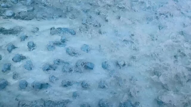 Aerial view of blue water flowing over rocky textured surface