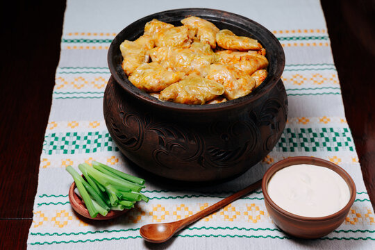 A traditional Moldovan clay pot filled with delicious sarmale is presented alongside sour cream and greenery, showcasing one of Moldova&rsquo;s most beloved and authentic national dishes.