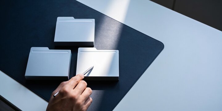 Internal audit document review background with blank file folders, pointer hand, focused light, dark office desk, copy space for report cover or business header