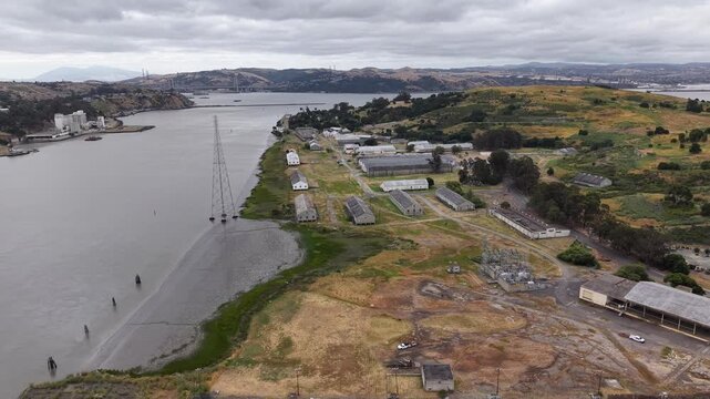VALLEJO, CALIFORNIA, USA - JUNE 19, 2026: Aerial view of the industrial waterfront at the historic Mare Island shipyard, with finger piers, a moored vessel, dockside cranes and a laydown yard.