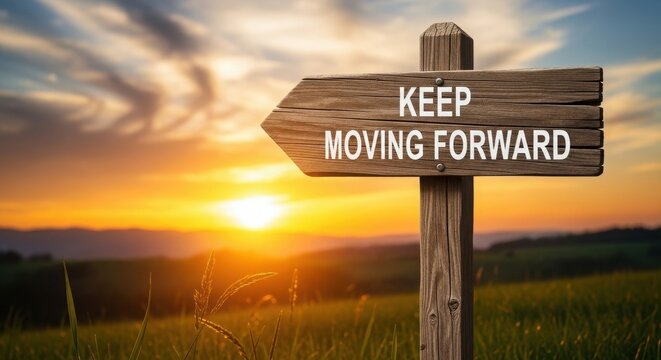 Wooden signpost with the text keep moving forward against a beautiful sunset sky and grassy field