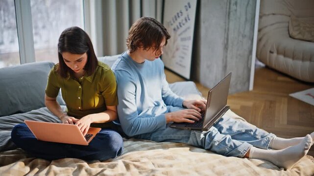 Girlfriend boyfriend browsing laptops soft bed closeup. Couple typing keyboards