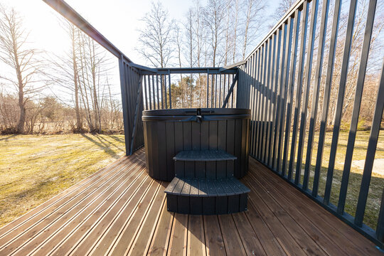 Compact round hot tub on deck with matte black slatted railings
