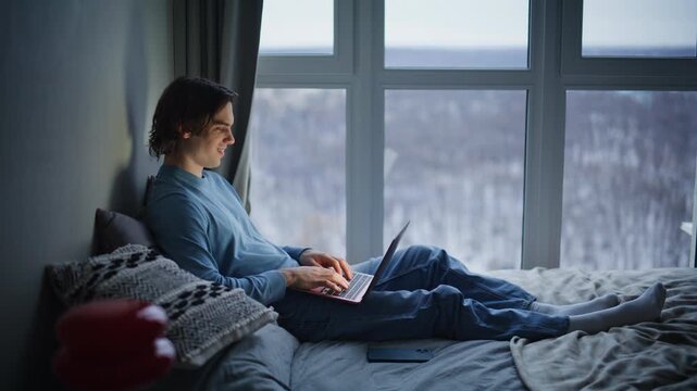 Bedding student using laptop evening home. Relaxed business man answering email