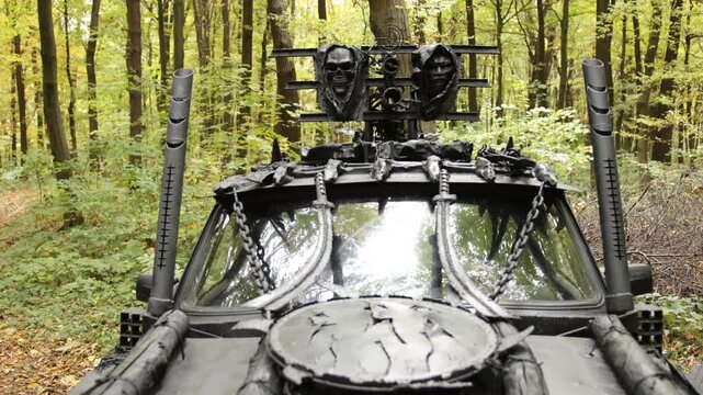 Menacing vibe, spiked vehicle, intimidating decor. Menacing vehicle with heavy armor, skull embellishments, and chains stands in forest, exuding post-apocalyptic atmosphere.