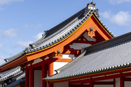View of the ornate vermilion beams and grey tiled roofs of a traditional Japanese temple under a clear blue sky in Kyoto, Kyoto, Japan.