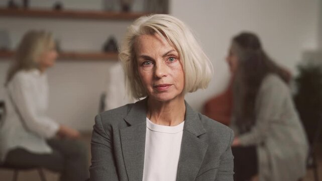 Portrait of empowered senior woman, beautiful old lady looking at camera in room . Women community and group therapy in psychological clinic, serious elegant female person, natural beauty and aging