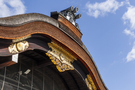 View of the ornate golden details and thatched roof of a traditional Japanese temple building under a blue sky in Kyoto, Kyoto, Japan.