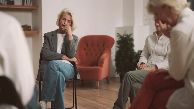 Senior woman talking about divorce or psychological troubles in group therapy. Modern mutual support group for people in difficult life situation, psychological help and supporting, ladies in circle
