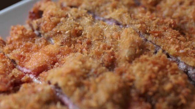 Delicious traditional spanish cachopo, a breaded veal fillet stuffed with ham and cheese, presented on a plate in extreme close up