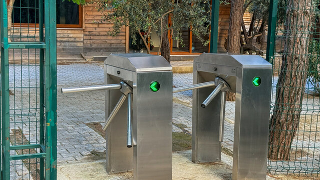 Stainless steel turnstiles at a gated park entrance in soft daylight ideal for security signage editorial, facility management and urban planning, 5 May 2026 Subitica, Serbia