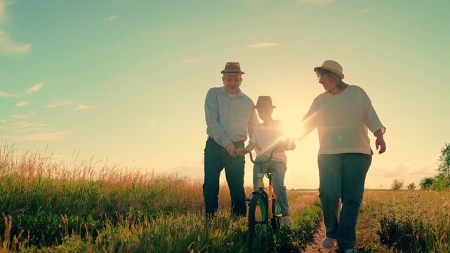 Family, parents, father, mother, daughter, riding bicycle outdoors, sun. Papa mama daughter with bicycle, helping with schoolwork. Family picnic outdoors. Happy people. Dad mom child, relaxing in park