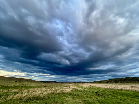 View of dramatic storm clouds gathering over a vast green savanna with rolling hills in the distance Waterberg District Municipality, Limpopo, South Africa.