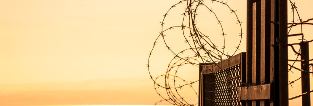 High-security prison area with barbed wire fencing and restricted access, symbolizing confinement, law enforcement, controlled environment, and strict protection of a secure facility.