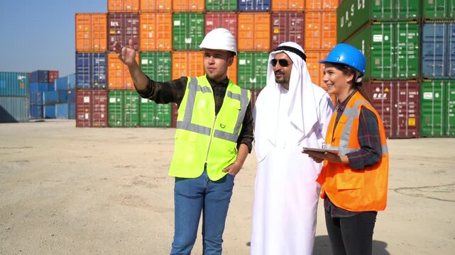 Arab businessman in kandura and logistics workers in masks discussing cargo details with digital tablet in front of colorful shipping containers stock video.