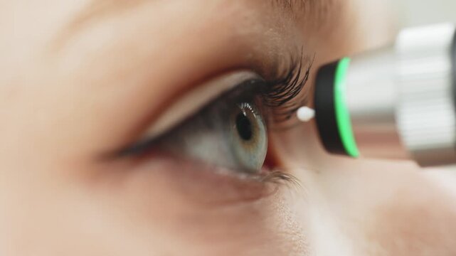 Close-up of Caucasian female patient undergoing eye examination with portable ophthalmic diagnostic device, focusing on eye and device interaction in clinical setting