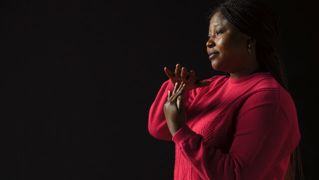 Side-view portrait of female model performing timeout, pause motion on camera, with African American woman in Black background displaying a t shape stop symbol with her arms, indicating no.