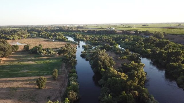 Drone flyover winding river agricultural fields sunset