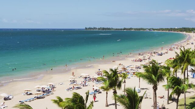 Isla Verde Beach in Puerto Rico. Tourist destination for beach resort and cruise ship tourists. Unrecognizable people enjoying beach summer holiday vacation on Caribbean travel. SLOW MOTION VIDEO.