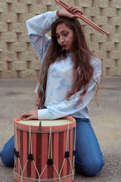 Young woman drummer posing with drumsticks and drum