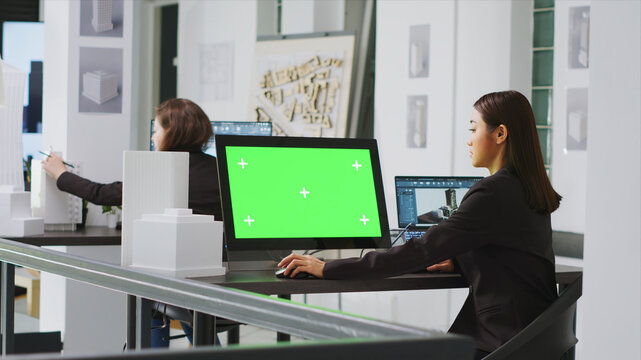 Architect using computer with green screen at workstation in agency office, looking at blank mockup template on monitor, engineer employed at a real estate small business, tripod shot.