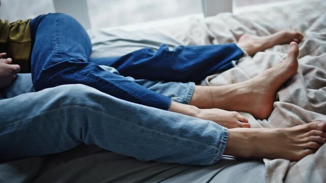 Couple legs lying bedding relaxing together closeup. Lovers boding each other