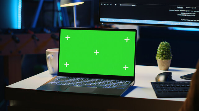 Green screen laptop in home office used for developing software applications, mockup notebook used by teleworking IT specialist for programming, close-up panning shot.