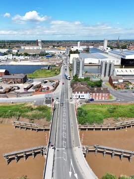 Aerial view of the Ouse Bridge spanning the river with industrial warehouses, storage silos, and road traffic in the background in Goole, England, United Kingdom.