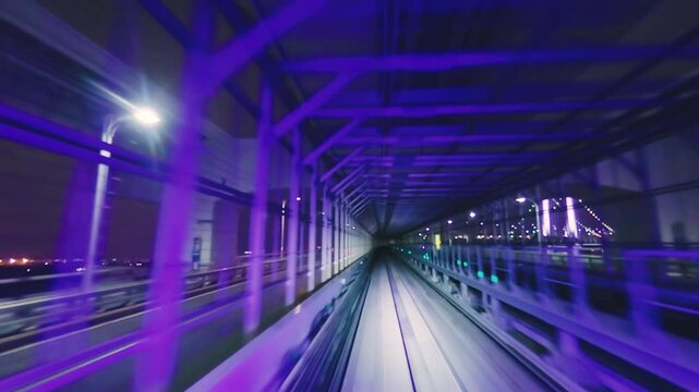 Train window view of riding through the illuminated Rainbow Bridge structure at night in Tokyo