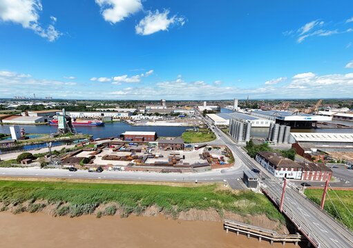 Aerial view of the industrial port area featuring warehouses, storage silos, a canal, and a bridge under a blue sky in Goole, England, United Kingdom.