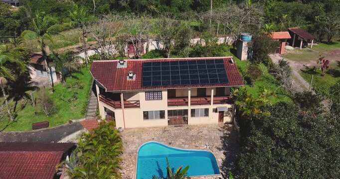 4K drone view of house with rooftop solar panels and swimming pool, showcasing renewable energy and sustainable living in countryside.