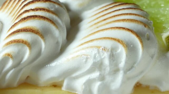 Panning shot of toasted meringue swirls on key lemon pie macro video footage showing caramelized texture and golden peaks