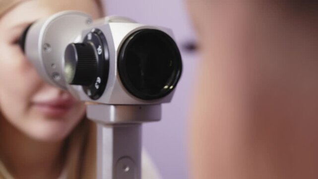Female patient undergoing eye examination with slit lamp and optical equipment, close-up view of the examination process in a clinical setting