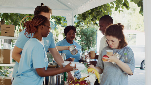 Warm meals are given to the underprivileged by humanitarians through a non-profit organization, volunteers distributing free food and essentials to the needy during an outdoor food drive.