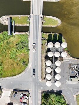 Aerial view of a bridge crossing a waterway next to industrial grain silos and a road with vehicles in Goole, England, United Kingdom.