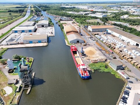 Aerial view of a cargo ship docked at the industrial port of Goole, surrounded by warehouses, storage facilities, and canal infrastructure in Goole, England, United Kingdom.