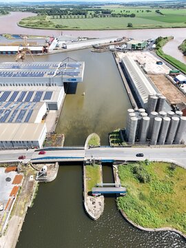 Aerial view of the industrial docks featuring a canal lock, storage silos, warehouses with solar panels, and a bridge crossing the water in Goole, England, United Kingdom.